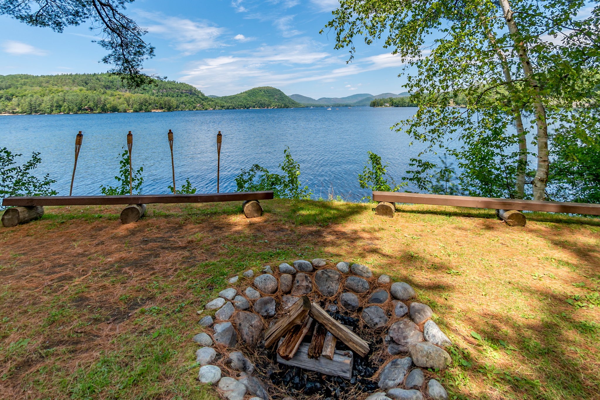 The campfire circle at Point O'Pines, with log benches and a stone fire pit looking out over Brant Lake