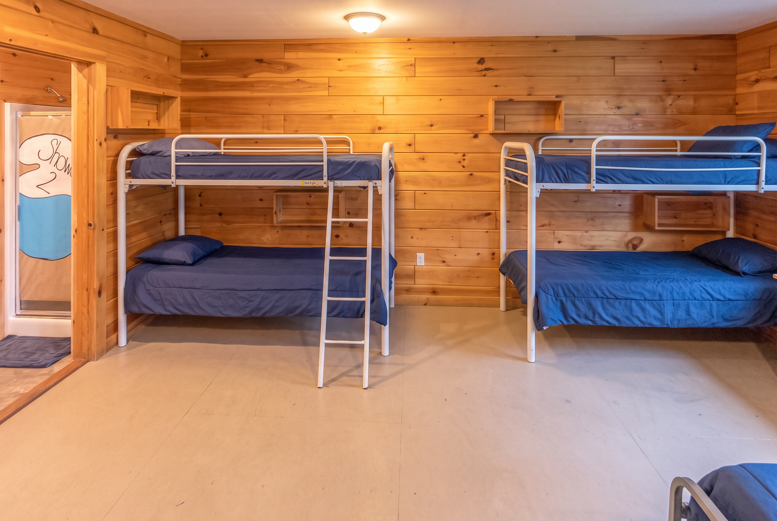 A tidy wooden bunk cabin at Point O'Pines with plain navy bedding, ready for campers