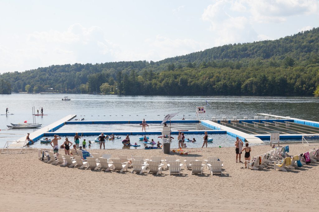The waterfront on Brant Lake at Point O'Pines, with swimming docks and the Adirondack hills behind